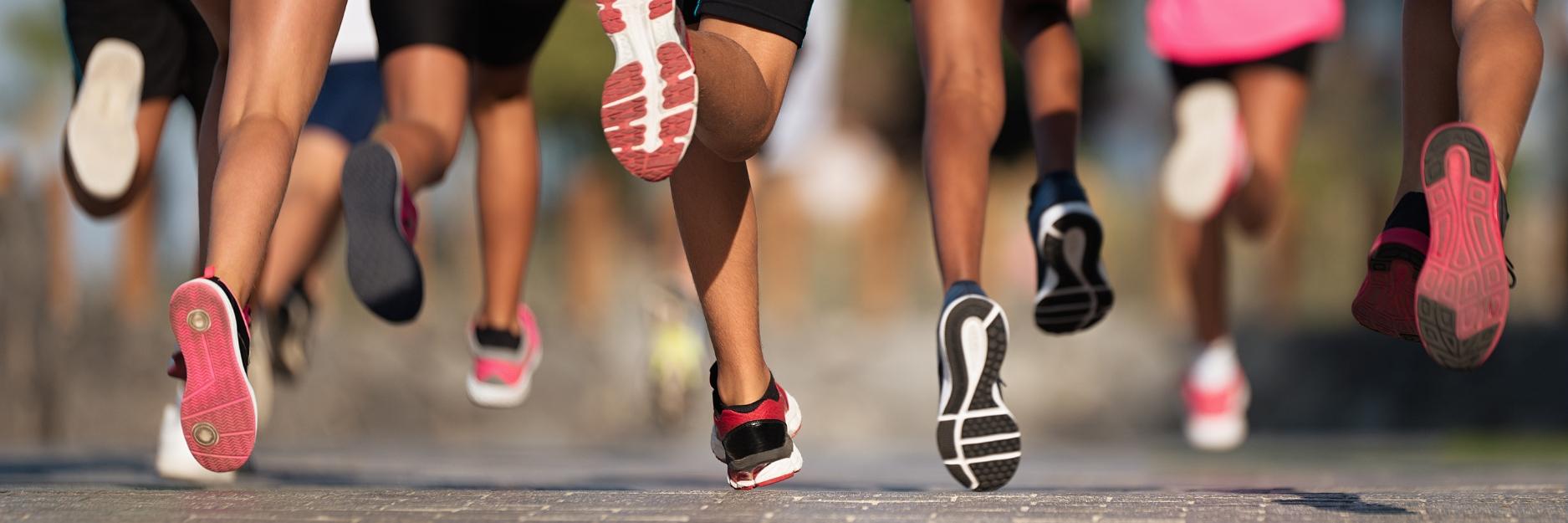 Women's legs with pink trainers running in marathon race